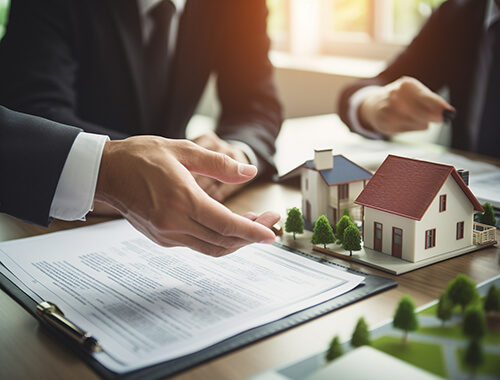 Property deal paperwork with home model on desk