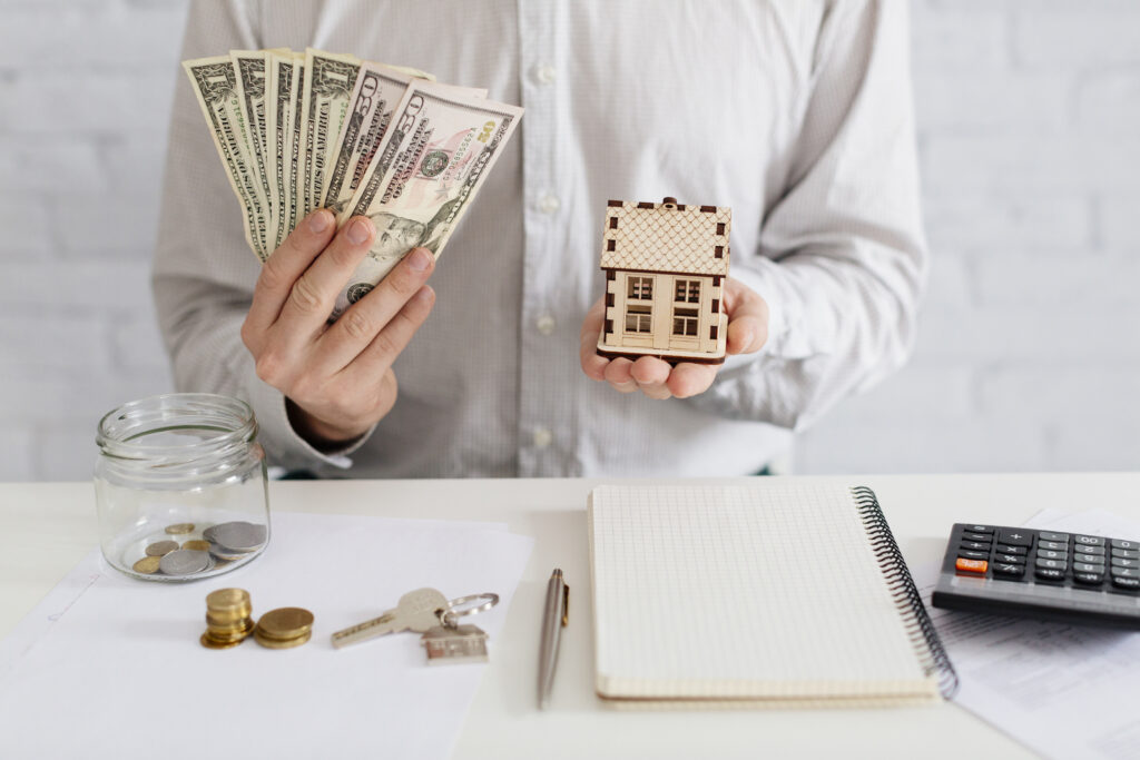 Home seller holding cash and house model after sale